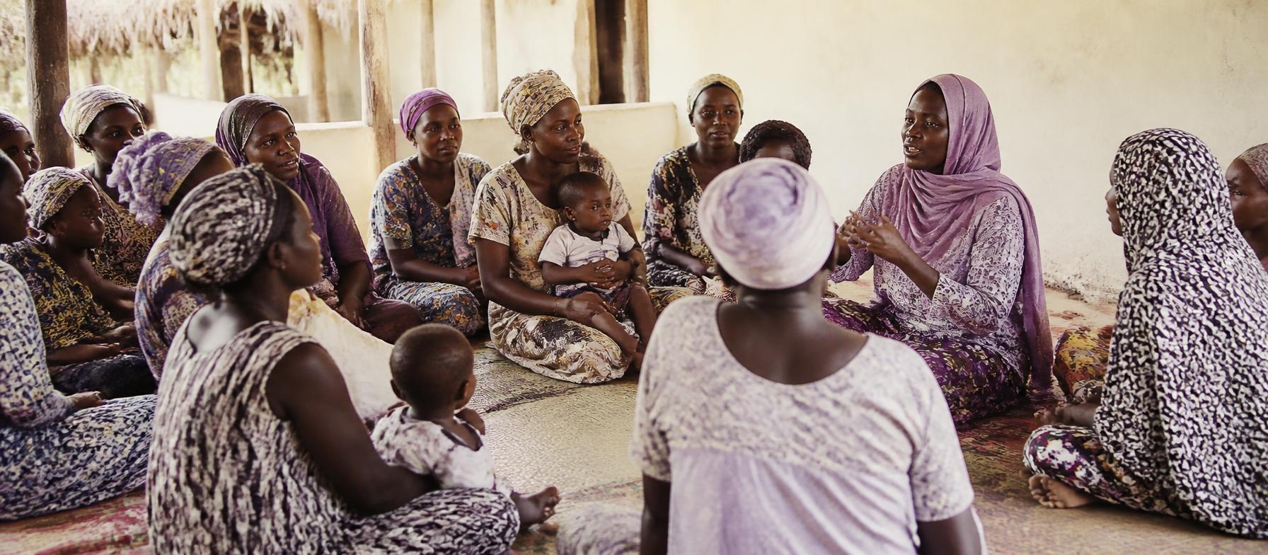African mothers gathered in a circle in a sunlit community space